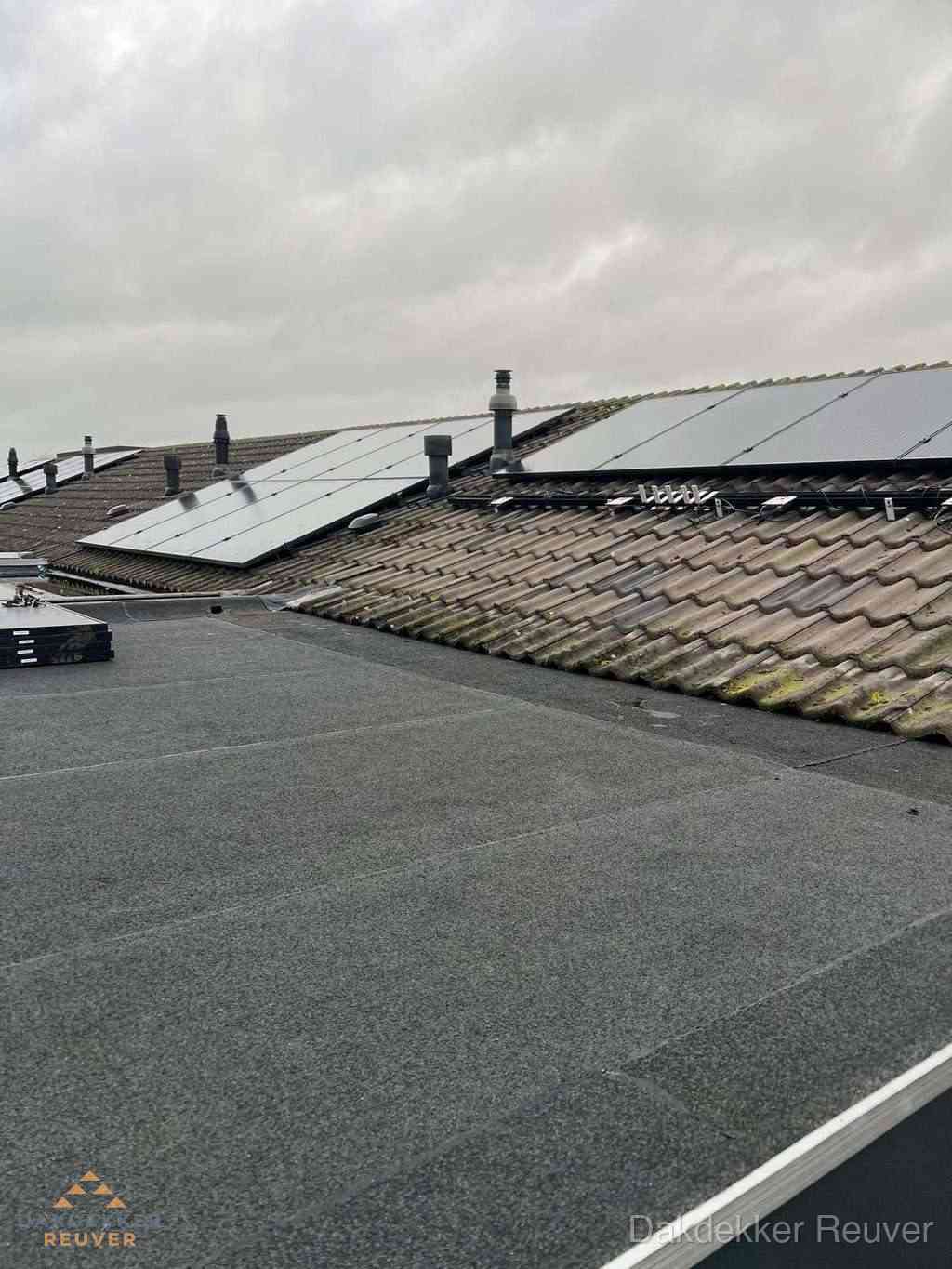 Plat dak inspectie met bitumen bedekking naast schuin pannendak in Reuver